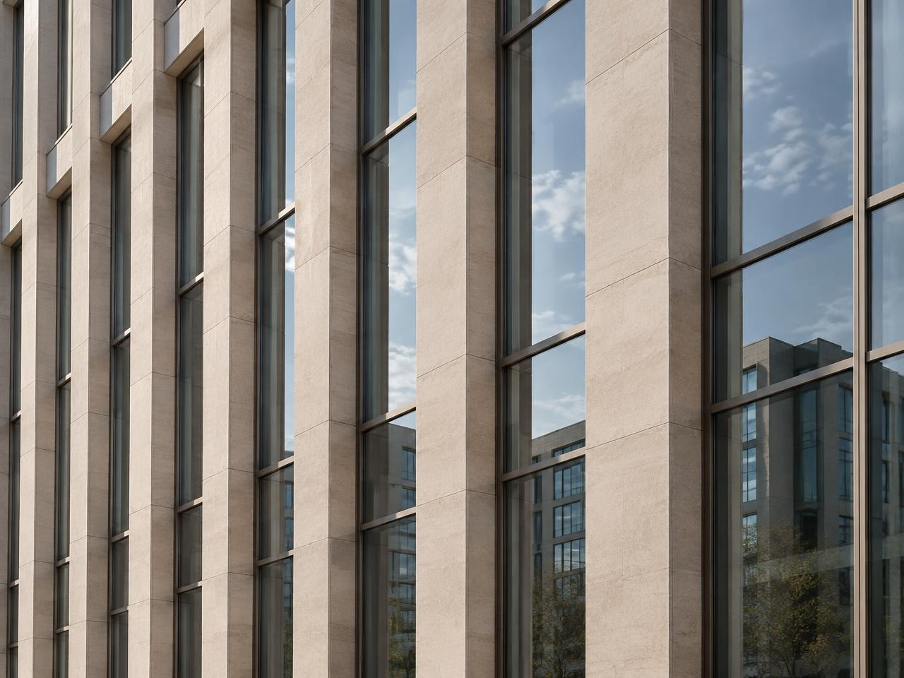 Close view of a modern office facade with repeating stone piers and glass panels
